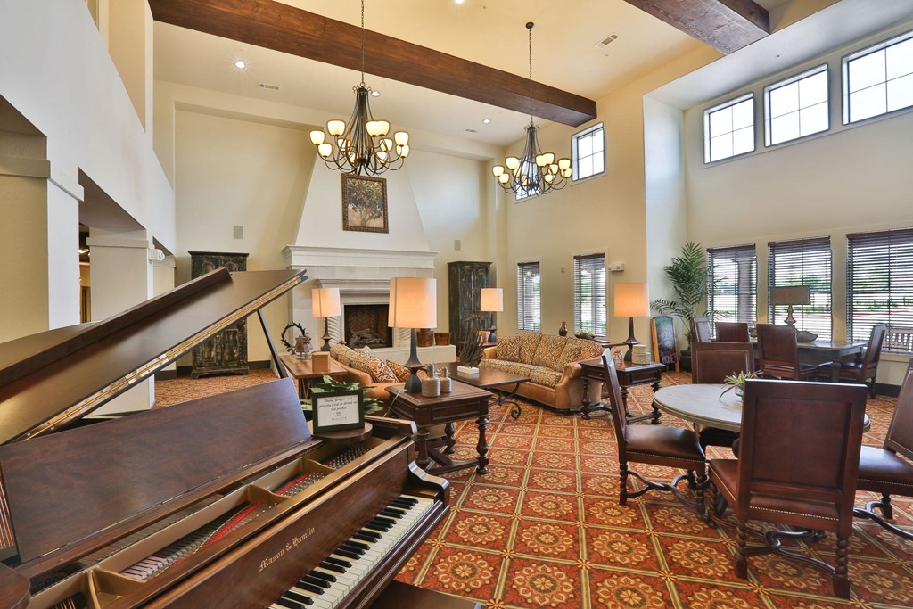a large living room with a piano and a fireplace at Cedars of Elk Drive 55+ Apartments, Burleson