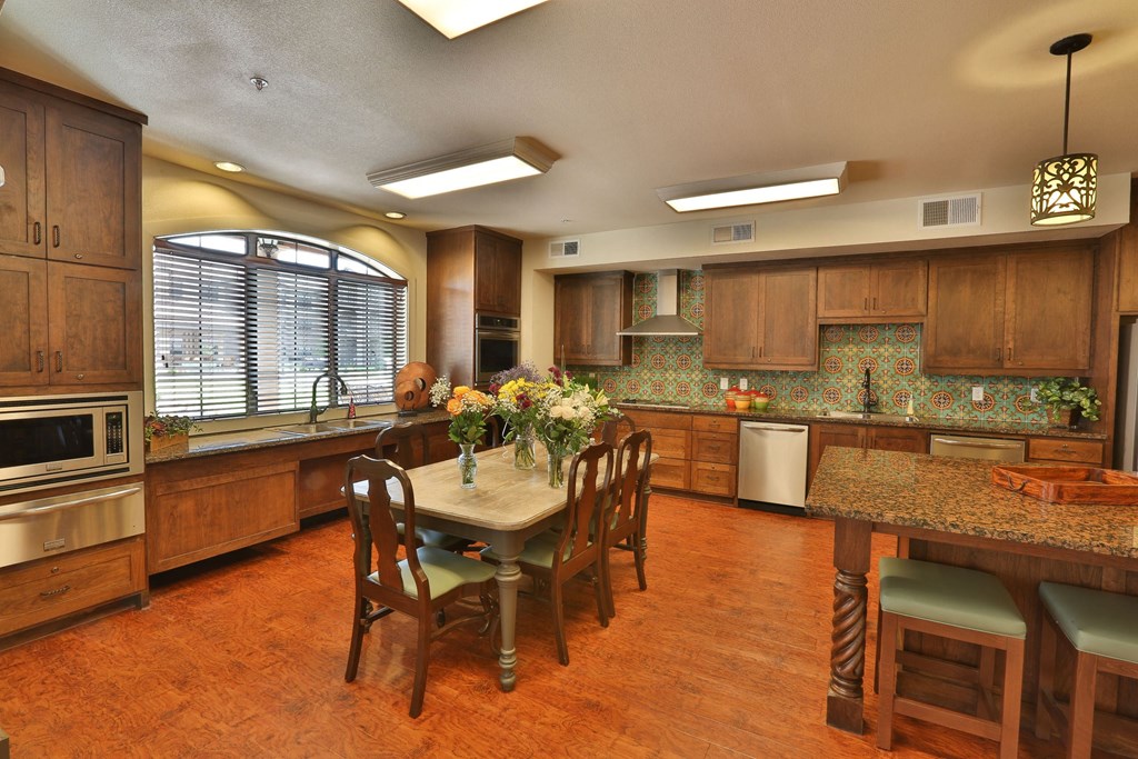 a large kitchen with a large island and a table with chairs at Cedars of Elk Drive 55+ Apartments, Burleson, TX 76028