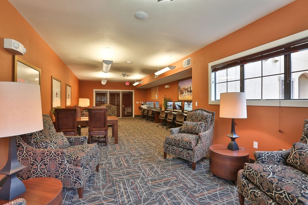 a lounge area with chairs and tables and a large window at Cedars of Elk Drive 55+ Apartments, Burleson, 76028