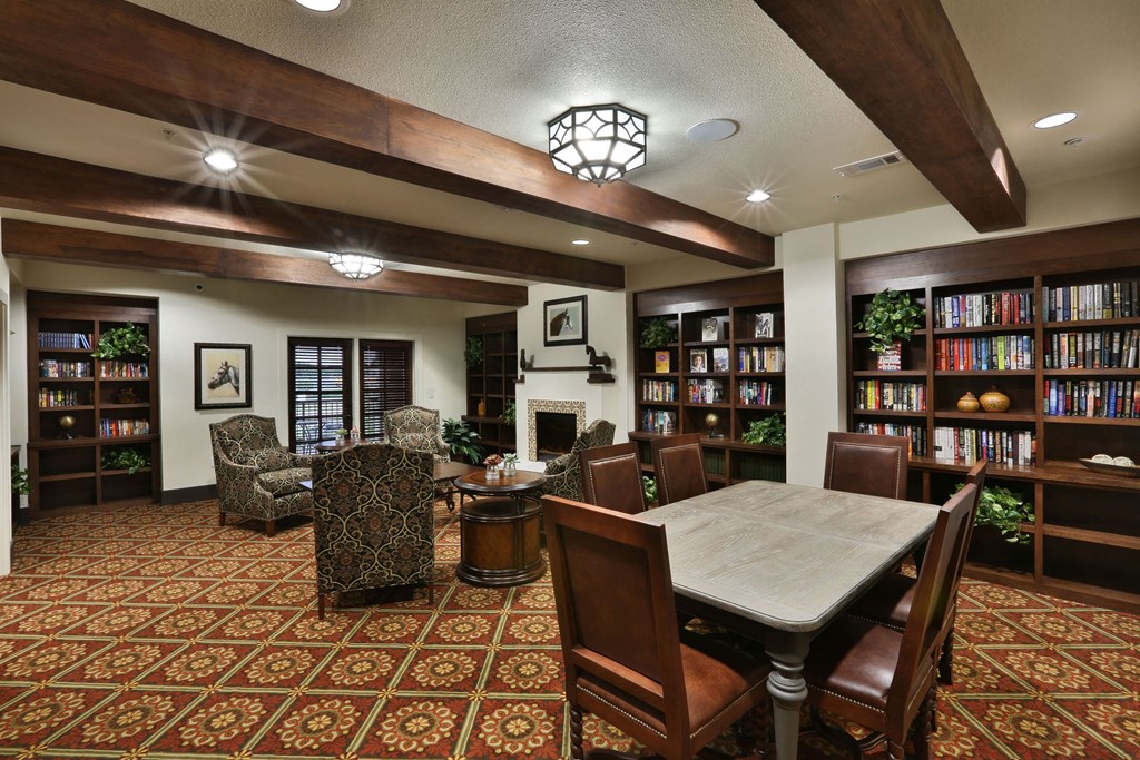 a library with a table and chairs and a fireplace at Cedars of Elk Drive 55+ Apartments, Burleson Texas