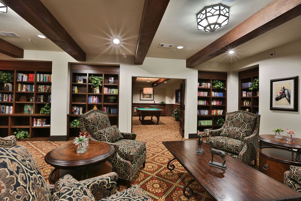 a game room with a pool table and book shelves at Cedars of Elk Drive 55+ Apartments, Burleson