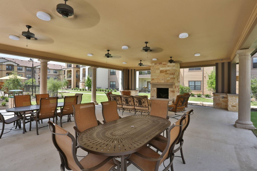 a patio with tables and chairs and a fireplace at Cedars of Elk Drive 55+ Apartments, Texas, 76028