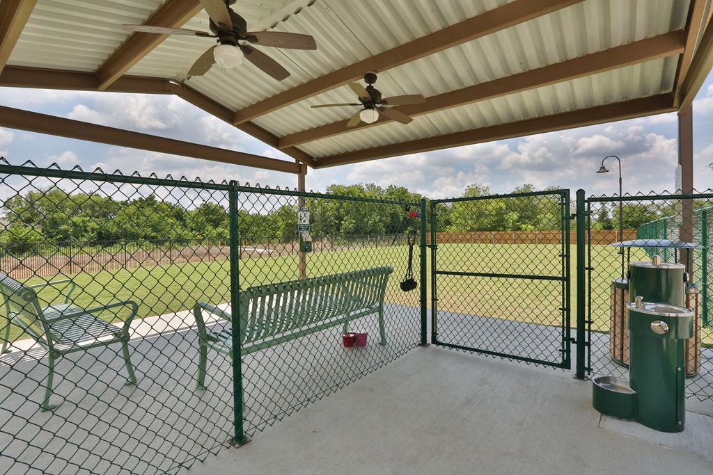 a patio with a bench and a chain link fence at Cedars of Elk Drive 55+ Apartments, Burleson, TX