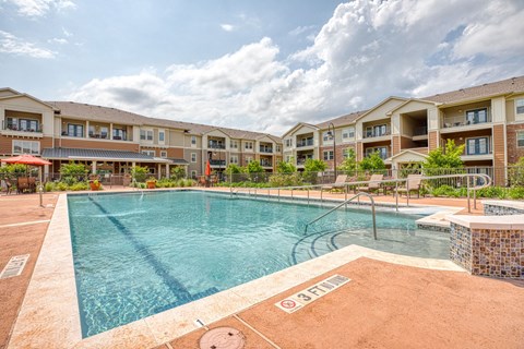 a swimming pool with an apartment building in the background at Sylvia at South Broadway 55+ Apartments, Texas
