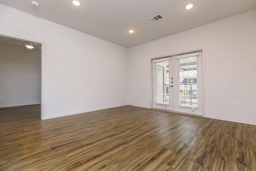 a living room with white walls and wood flooring and a door to a balcony at Mariposa at Westchester, Texas