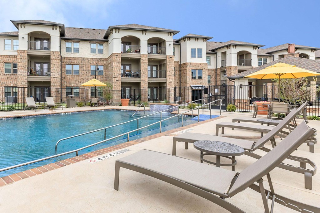 our apartments offer a swimming pool with lounge chairs and umbrellas at Mariposa at Westchester, Grand Prairie, TX