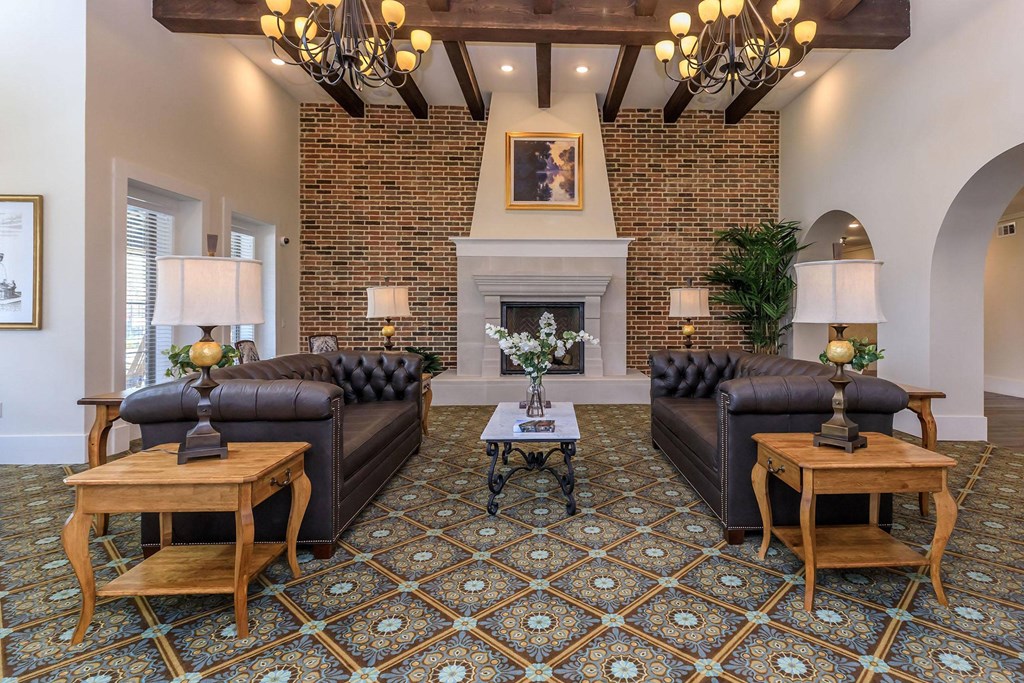 a living room with leather couches and a brick fireplace at Mariposa at Westchester, Grand Prairie