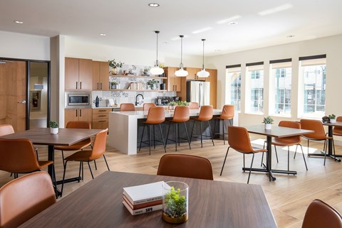 A modern kitchen with orange chairs and a wooden table.