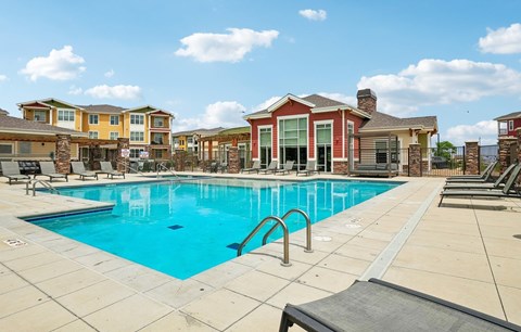 A large swimming pool in front of a building with a red roof.