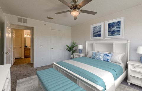 A bedroom with a large bed and a ceiling fan.