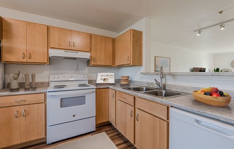 A kitchen with wooden cabinets and a white stove top oven.