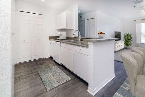 A kitchen with white cabinets and a rug on the floor.