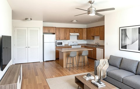 A modern kitchen with a dining table and a grey sofa.