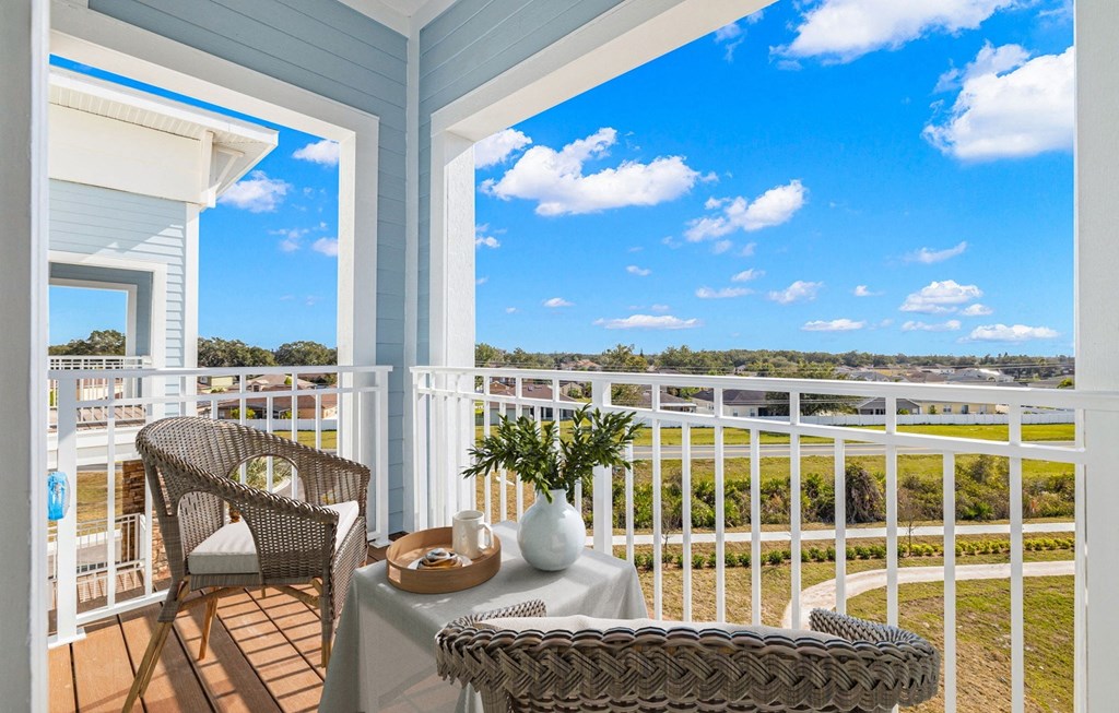 a balcony with two chairs and a table and a view of the water  at Osprey Park 62+ Apartments & Cottages, Kissimmee, FL, 34758
