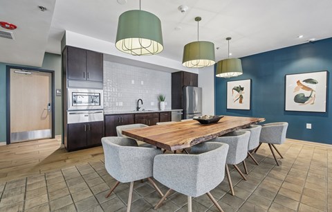 A modern kitchen with a wooden dining table and grey chairs.