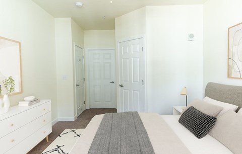 A white bedroom with a large bed and a dresser.