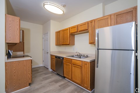 A kitchen with a refrigerator, sink, and cabinets.