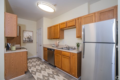 A kitchen with a refrigerator, sink, and cabinets.