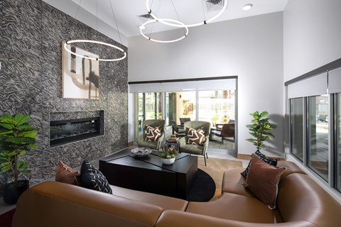 A living room with a brown leather couch and a television on the wall.