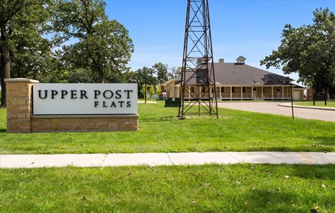 A sign that says Upper Post Flats in front of a building.