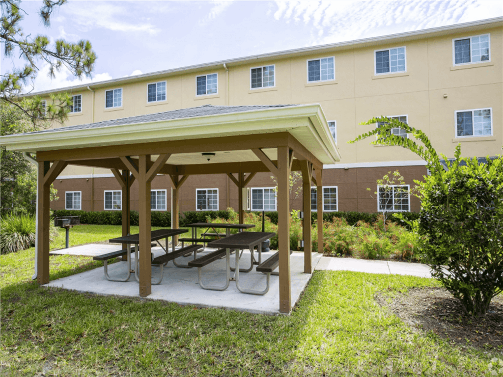 A covered picnic table is in front of a building.