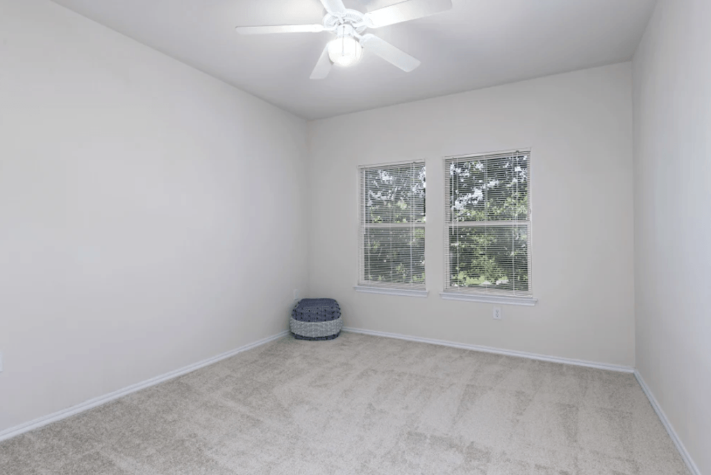 a white room with two windows and a ceiling fan at Belle at Bay Colony 55+ Apartments, Dickinson, TX