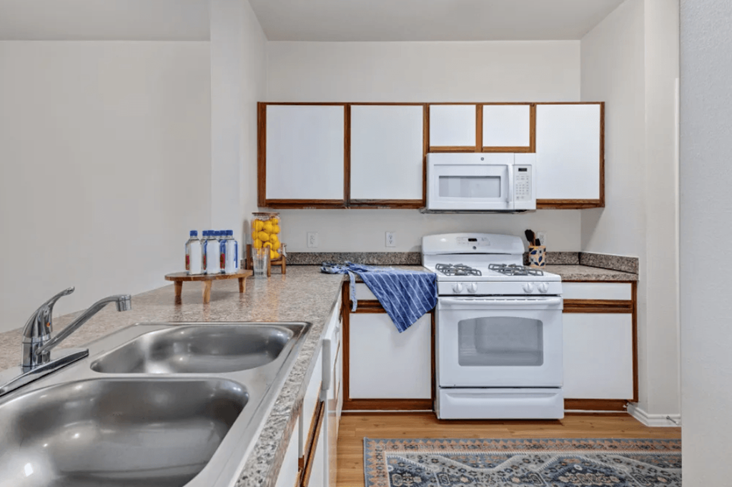 a kitchen with a sink and a stove and a microwave at Belle at Bay Colony 55+ Apartments, Dickinson