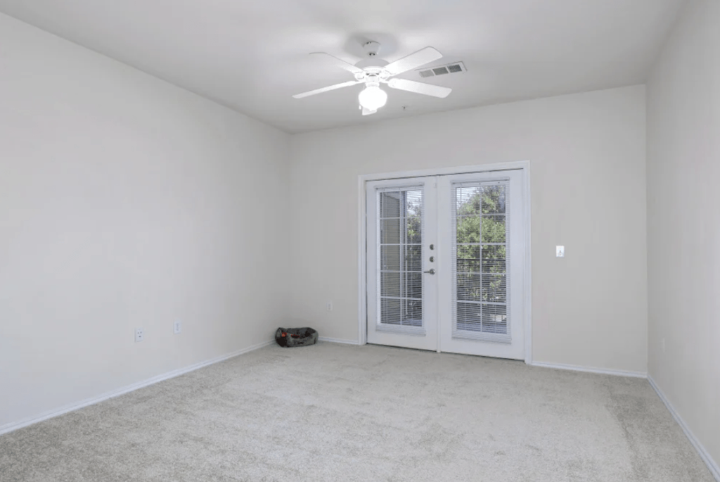 an empty living room with a ceiling fan and a window at Belle at Bay Colony 55+ Apartments, Dickinson, TX 77539
