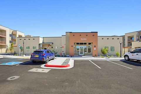 A blue car is parked in a parking lot in front of a building with the number 3200 on it.