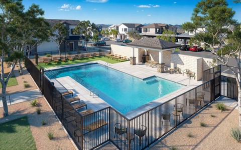 A pool surrounded by a black fence with a small patio area at Sidney Village, Buckeye, AZ 85326