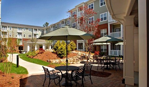 A patio with a table and chairs is surrounded by apartment buildings.