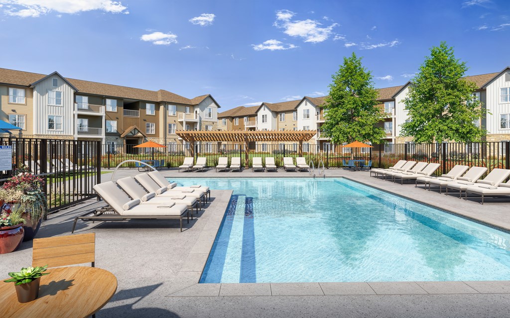 A pool surrounded by lounge chairs and trees.