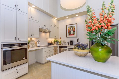 A kitchen with white cabinets and a green vase on the counter.