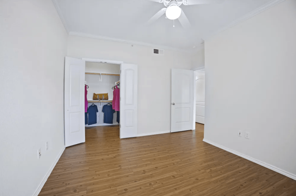 a living room with white walls and wood floors at Ten 06 at Joshua Station Apartments, Joshua, TX 76058