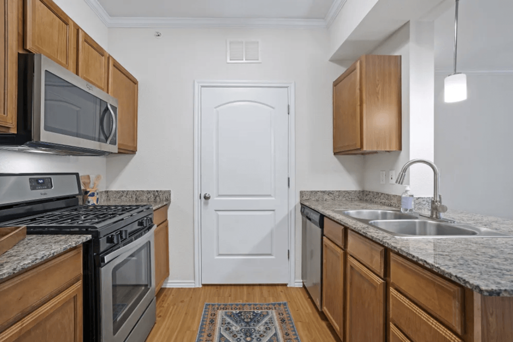 a kitchen with granite counter tops and wooden cabinets at Ten 06 at Joshua Station Apartments, Texas, 76058