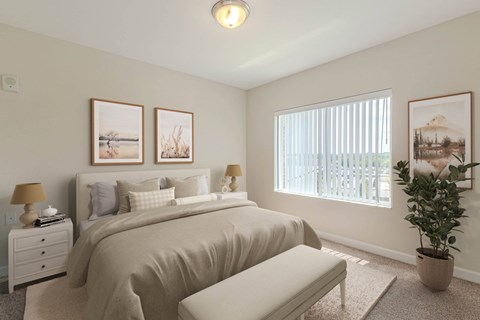 A bedroom with a large bed, a nightstand with a lamp, a bench, and three pictures on the wall. at Avery Landing Apartments, Greenville