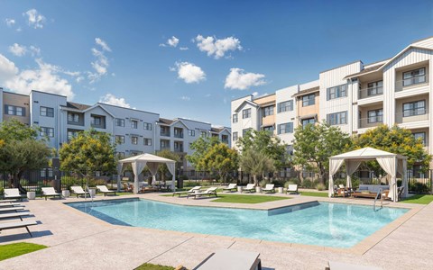 A swimming pool surrounded by lounge chairs and umbrellas in front of apartment buildings at Orchard Springs 55+ Apartment , Surprise, 85374