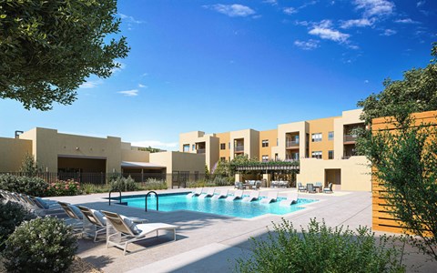A pool area with sun loungers and a building in the background at Sandoval Flats Apartment , Rio Rancho, MN