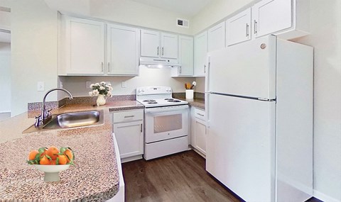 Contempo kitchen with sleek white cabinetry, white appliances, dishwasher, bistro bar, granite countertops and easy-care wood plank flooring.