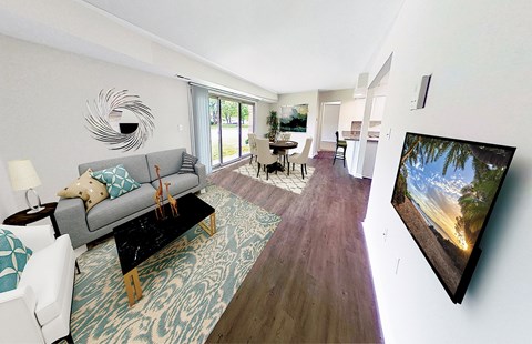 A living room with a grey couch and a television on the wall.