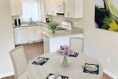 Kitchen/Dining Nook in Weatherstone Townhomes with wood plank flooring, modern appliances, upscale cabinets and countertops.