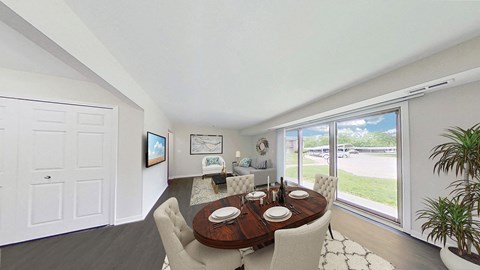 A dining room with a table set for two and a view of the backyard.