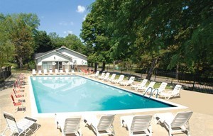 A pool with chairs around it and a house in the background.