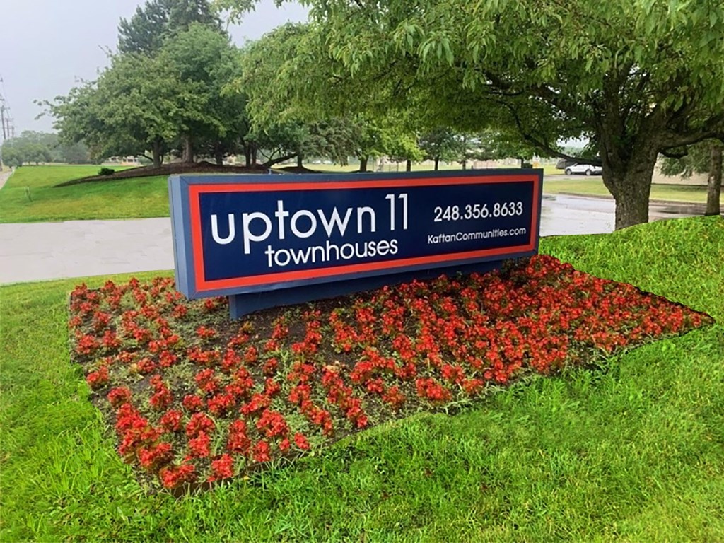 A sign for uptown 11 townhouses with a phone number and website.