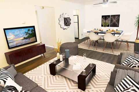 A living room with a grey sofa, a wooden entertainment unit, a coffee table, and a dining table set up.