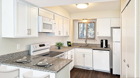 A kitchen with white cabinets and granite countertops.