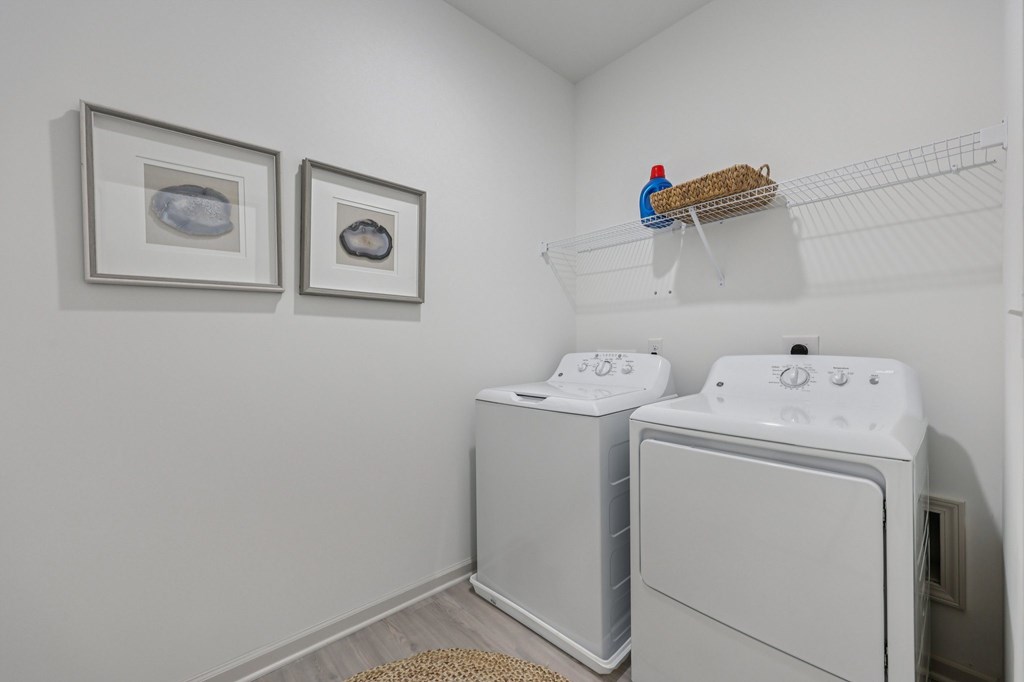 A laundry room with two washing machines and two pictures on the wall.