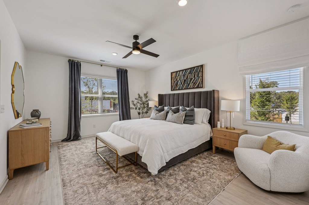 A bedroom with a large bed, a chair, and a ceiling fan.