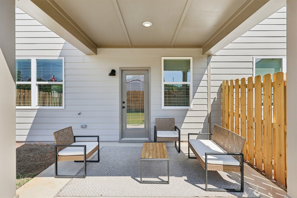 A patio with a bench and a table outside a house.