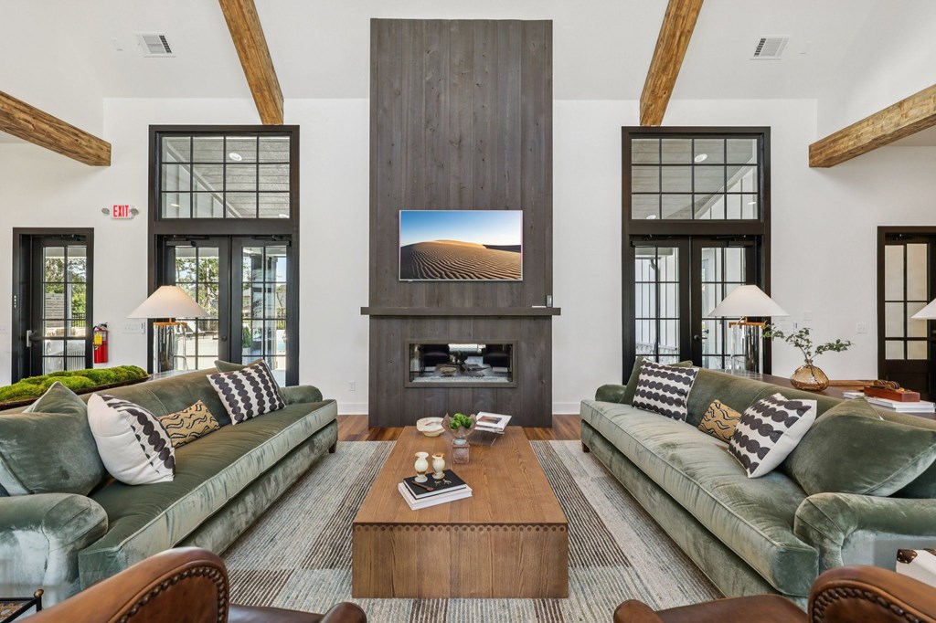 A living room with a green couch, a wooden coffee table, and a large screen on the wall.